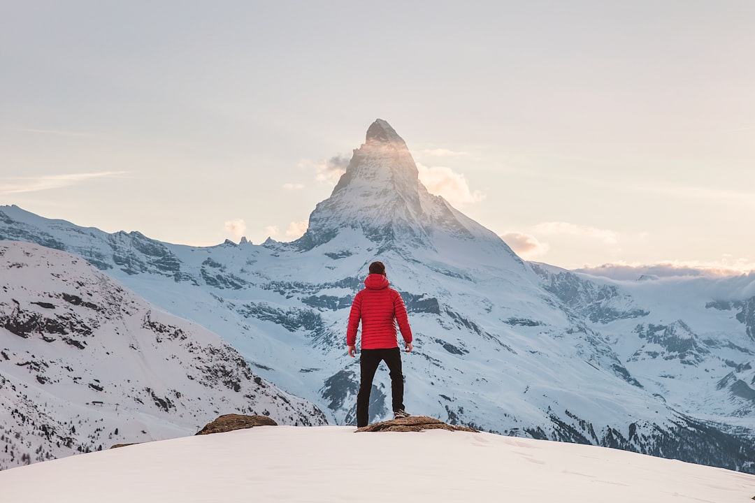 Photo by Joshua Earle person in red hoodie standing on snowy mountain during daytime